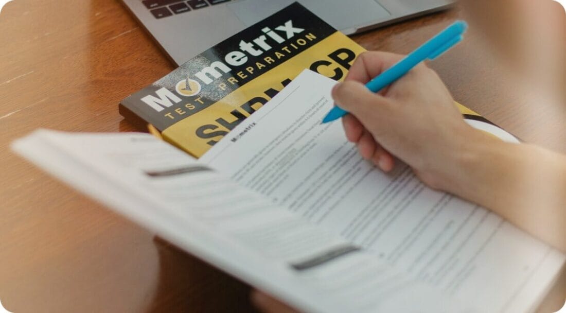 Person studying and writing on a book for test preparation