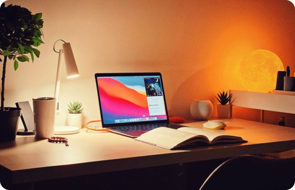 a laptop and a open book in a study room with good ambient