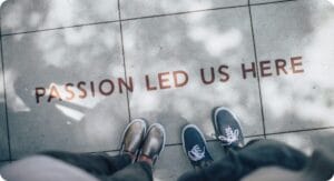 two people standing on a ground heading to a phrase on the ground saying PASSION LED US HERE