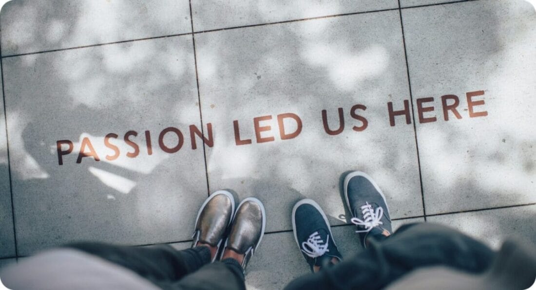 two people standing on a ground heading to a phrase on the ground saying PASSION LED US HERE