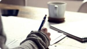 CMA 시험 파트 2 공부법: Part 2 합격을 위한 전략 가이드 4 a person studying on a brown wooden table near a white mug