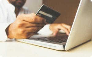 a man holding credit card in front of a laptop
