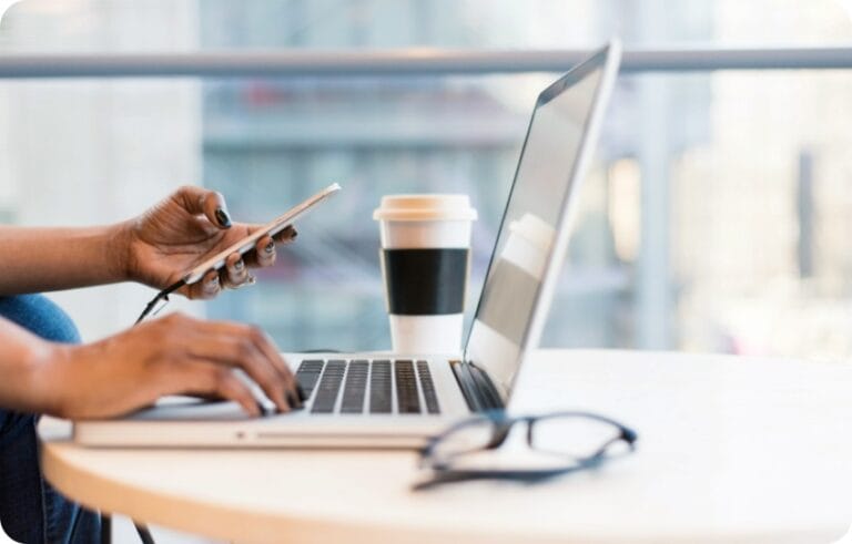 a person doing status check on a computer holding a cellphone