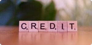 6 pink wooden blocks spelling CREDIT on a table