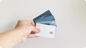 holding four credit cards from different credit card companies including apple, American Express, Discover and Capital One