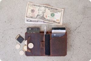 US bills and a brown leather wallet with credit cards and coins sticking out