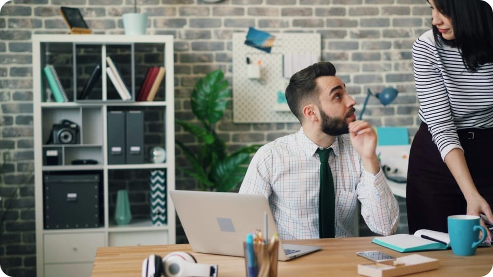 a man and a woman looking at each other in an office working together