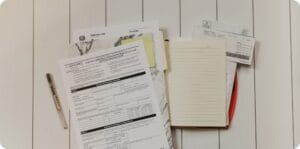a stack of tax documents and note laying on a ground next to a pen