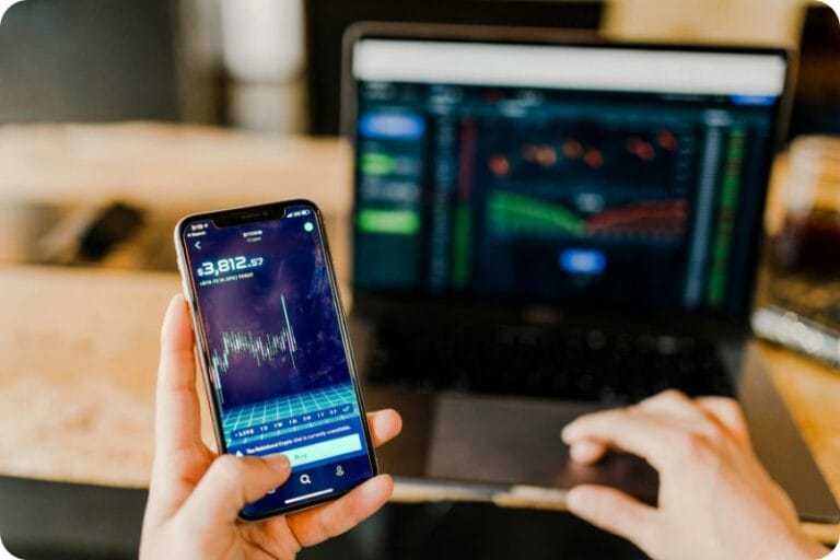 401(k) 롤오버 방법: 이직 시 401(k) 안전하게 옮기는 법 1 a cellphone app and a laptop showing an financial investment chart