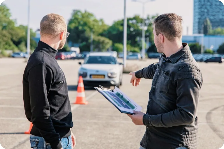Driving instructor explaining to a student with traffic cone
